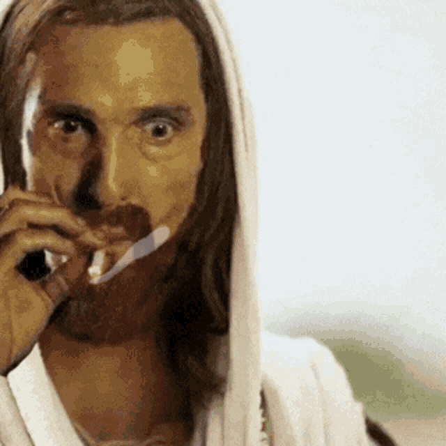 a man with long hair and a beard brushing his teeth