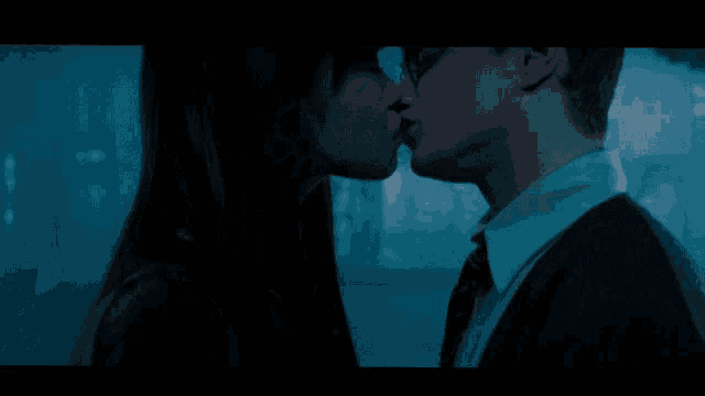 a man and a woman kissing in front of a building