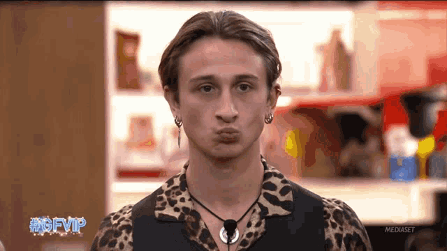 a man wearing a leopard print shirt is making a face