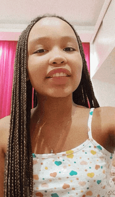 a girl with braids and a white tank top with hearts on it