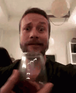 a man with a beard is holding a glass in his hand