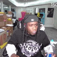 a man wearing headphones and a supreme shirt is holding a bottle