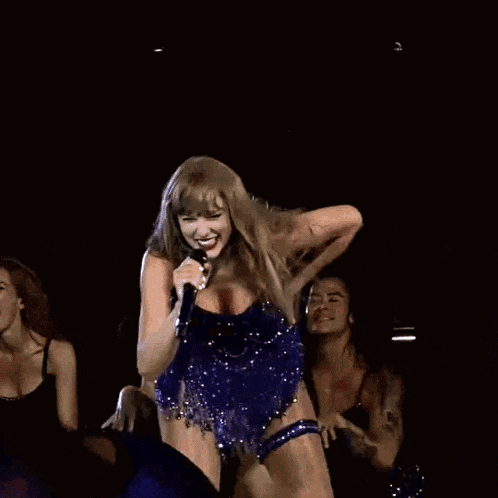 a woman in a blue dress is singing into a microphone on a stage