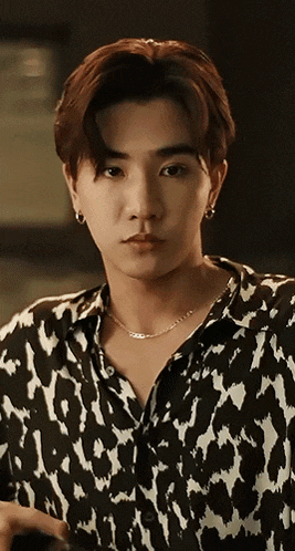a young man wearing a black and white shirt and a necklace