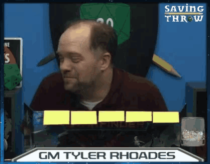a man is sitting in front of a screen that says gm tyler rhoades .