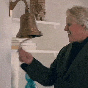 a man in a suit rings a bell on a wall