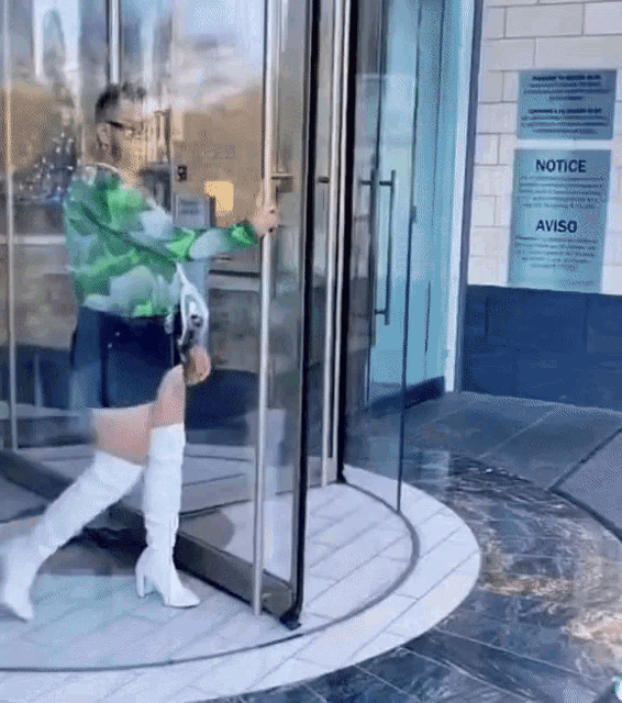 a woman in white boots is walking through a glass door with a sign that says notice aviso on it