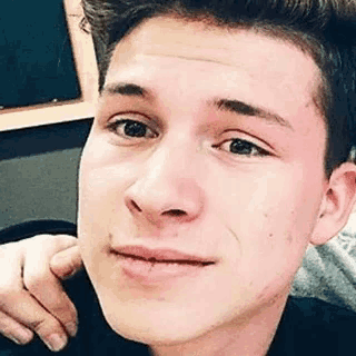 a close up of a young man 's face with his hand on his neck .