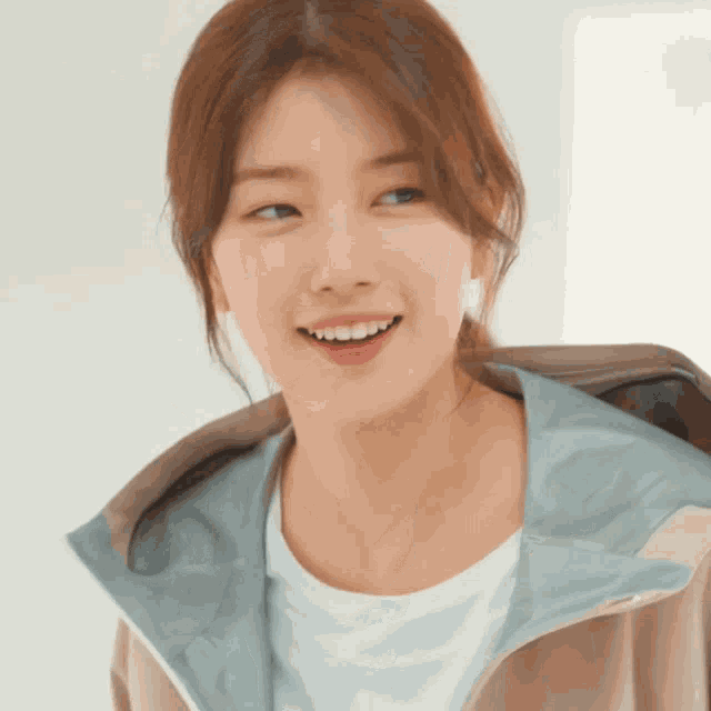 a woman wearing a jacket and a white shirt smiles