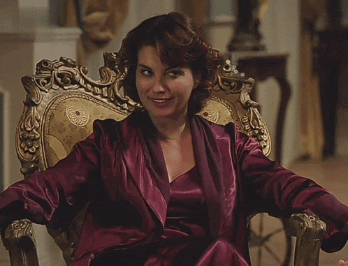 a woman in a purple robe sits in a gold chair