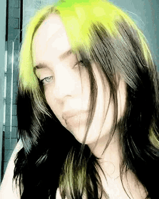 a close up of a woman 's face with black hair and green hair .