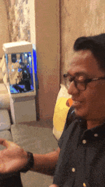 a man wearing glasses is sitting in front of a small fish tank