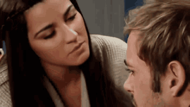a woman is kissing a man on the cheek in a close up