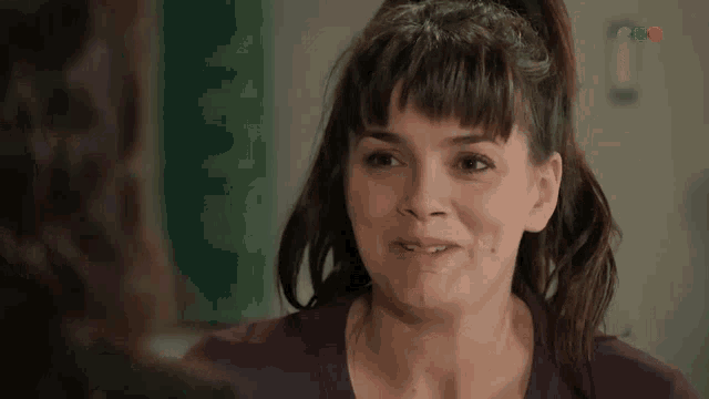 a woman in a purple shirt is smiling and looking at another woman
