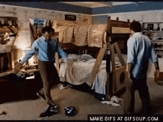 two men are dancing in a bedroom with a bunk bed .