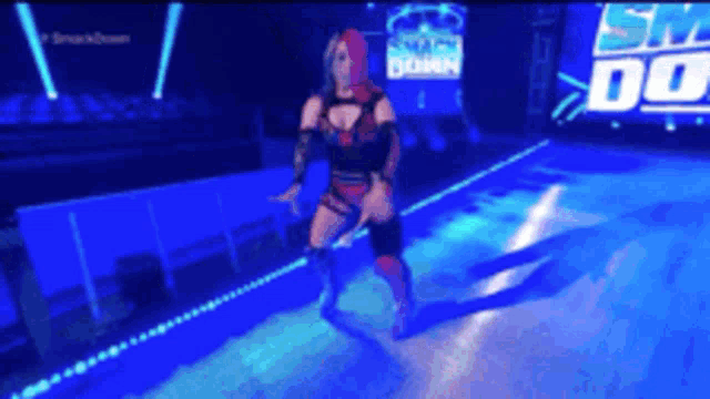 a female wrestler is dancing on a stage in front of a smackdown sign