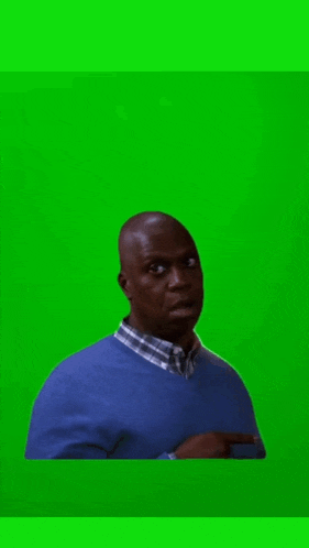a man in a blue sweater and plaid shirt is standing in front of a green background .