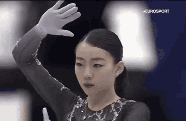 a female figure skater is wearing white gloves and a black top .