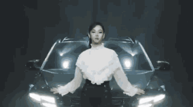 a woman in a white top is standing in front of a car .