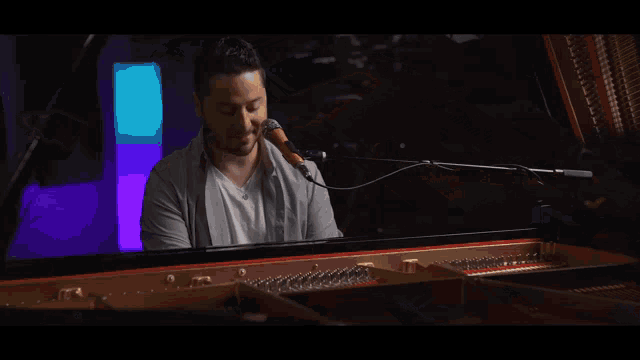 a man singing into a microphone while sitting at a piano