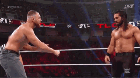 two men are wrestling in a wrestling ring with a referee standing behind them