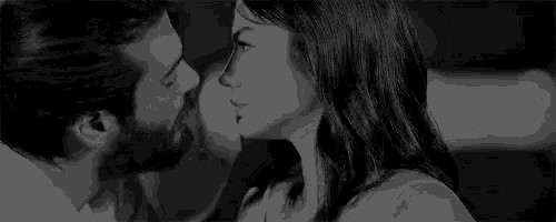 a black and white photo of a man and a woman kissing .