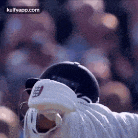 a close up of a cricket player wearing a helmet and gloves in front of a crowd .