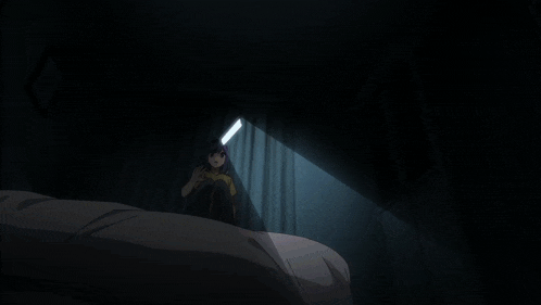 a girl is sitting on a bed in a dark room looking at a phone