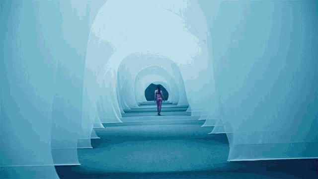 a woman is walking through a tunnel with a blue carpet