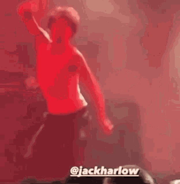 a man in a red shirt is dancing on a stage in front of a crowd with a caption that says jackharlow .