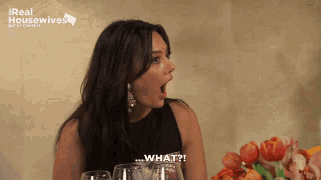 a woman is sitting at a table with wine glasses and a sign that says real housewives out of context