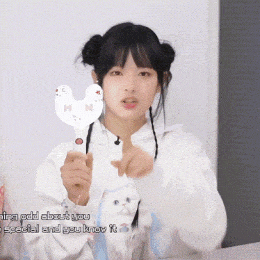a girl in a white hoodie is holding a stick that says " making odd about you "