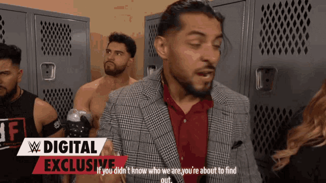 a man in a suit is talking to a woman in a locker room with a digital exclusive advertisement behind him