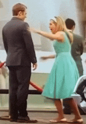 a man in a suit and a woman in a green dress are standing next to each other