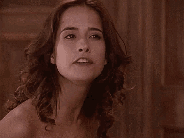 a woman without a shirt is smiling and looking at the camera