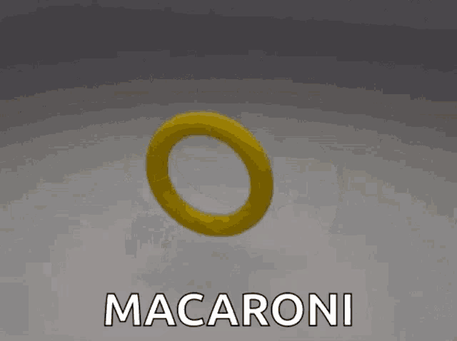 a yellow macaroni with two holes in it is moving on a white surface .