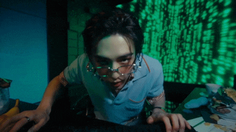 a man wearing glasses is typing on a computer