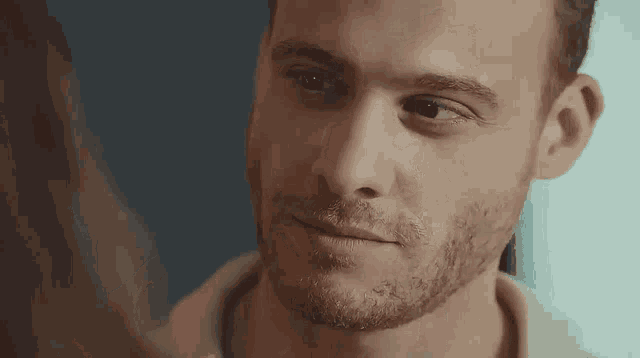 a close up of a man 's face with a beard and a woman looking at him .