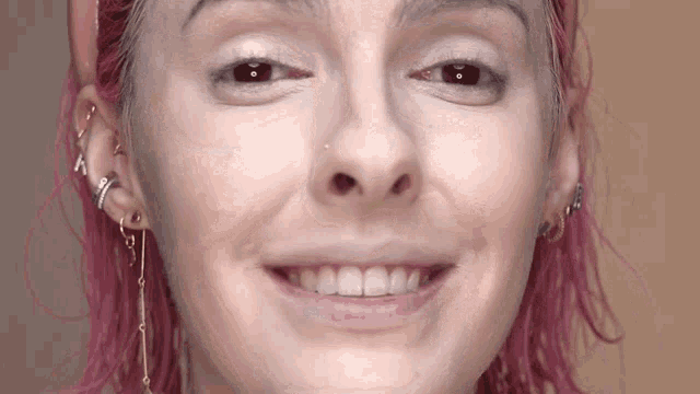 a close up of a woman 's face with pink hair making a funny face .