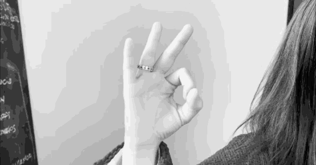 a black and white photo of a woman 's hand giving the ok sign
