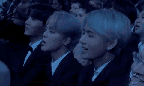 a group of people in suits and ties are sitting in a row .