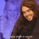 a man with long hair is smiling in front of a woman who is smiling in the background .