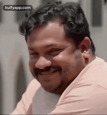 a man with a mustache is laughing with his eyes closed and his mouth open .
