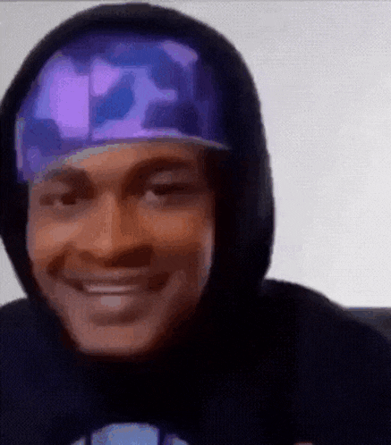 a man wearing a hoodie and a hat is smiling .