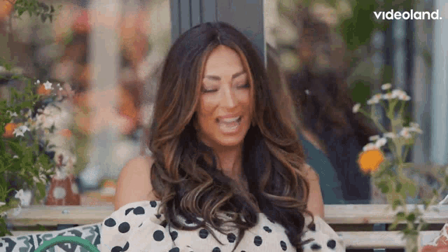 a woman in a polka dot dress is laughing with her eyes closed .