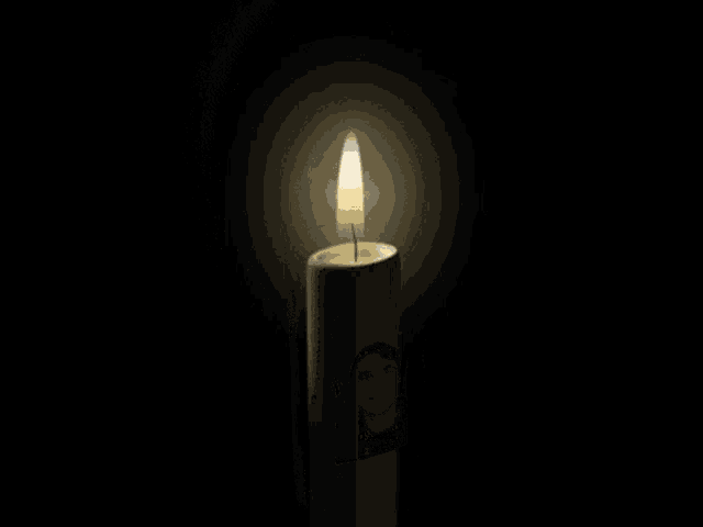 a candle with a picture of a man on it is lit up