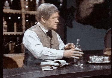 a man standing at a bar holding a bottle
