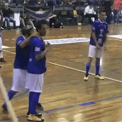 a group of soccer players are standing on a wooden court .