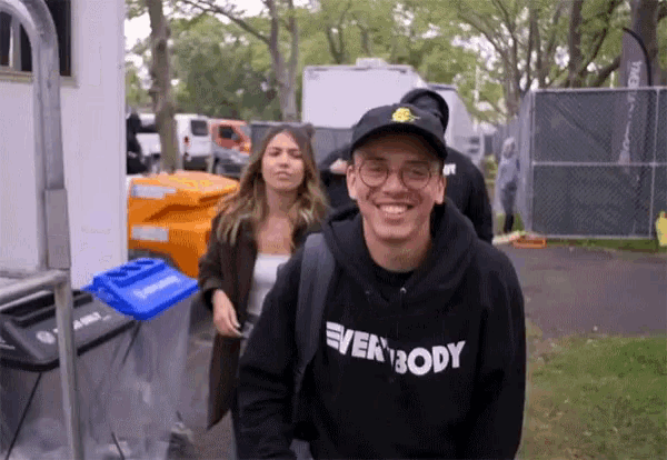 a man wearing a black hoodie that says everybody smiles for the camera