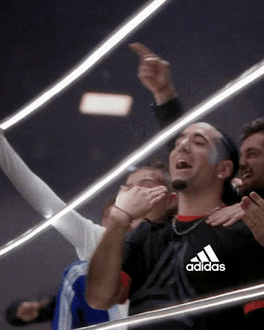 a man wearing a black adidas shirt applauds